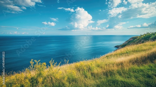 Coastal hillside overlooking the vast blue ocean, with the sky filled with soft clouds and plenty of copy space.