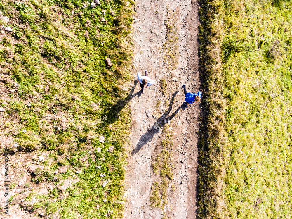 Fototapeta premium Aerial view of two runners jogging on dirt running trail in nature. Morning running training for friends.