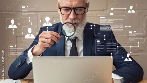 Businessman using magnifying glass to analyze data on a laptop, concept of data analysis, security, and recruitment. photo