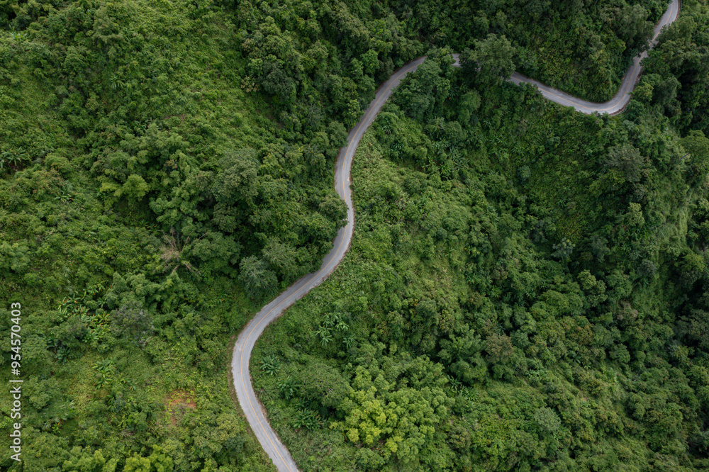 Aerial view on mountain road from drone of road in the middle of the forest in rainy day in spring, green foliage in empty asphalt road through the mountains. Aerial view on mountain road from drone of road in the middle of the forest in rainy day in spring, green foliage in empty asphalt road through the mountains.