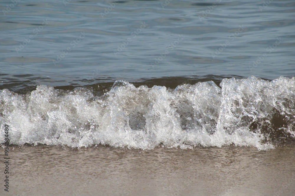 White foam and sea water drop splashes slow motion with sand and blue water White foam and sea water drop splashes slow motion with sand and blue water