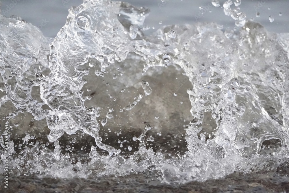 Obraz premium White foam and sea water drop splashes slow motion with sand and blue water
