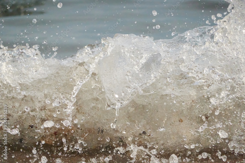 White foam and sea water drop splashes slow motion with sand and blue water