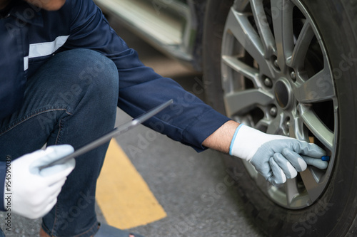 Asian male professional auto mechanic doing onsite service using tire changer wrench equipment. Inspect the damage according to the list and maintain the car on-site, emergency assistance service.