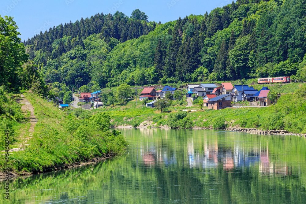 Fototapeta premium 千曲川に寄り添って暮らす家々の側を抜ける飯山線の観光列車