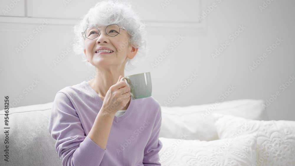 ソファーでコーヒーを飲みながらくつろぐシニア女性 ソファーでコーヒーを飲みながらくつろぐシニア女性