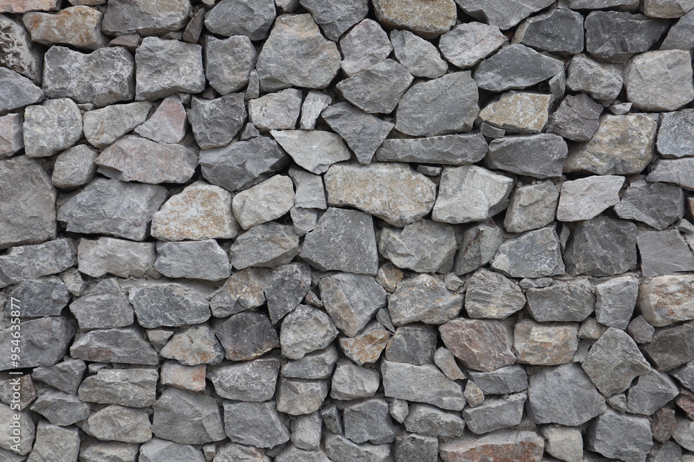 Wall constructed from rough, uneven stones in various shades of gray Wall constructed from rough, uneven stones in various shades of gray