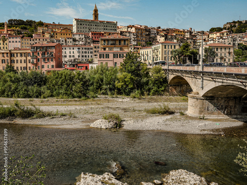 Charming Coastal Town Of Ventimiglia In Southern Europe With Colorful Houses, Lush Greenery, Vibrant Flowers, Serene River, And Clear Blue Sky Under The Warm Sun In Italy's Picturesque Land