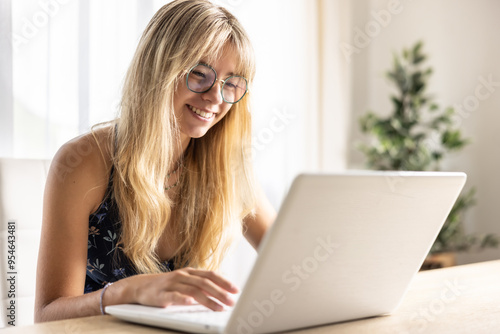 Portrait of happy young beautiful woman sitting with laptop, using glasses