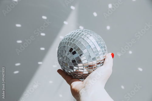 Hand holding a disco ball with reflected light spots photo