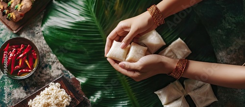 A woman s hand is preparing ketupat or Southeast Asian rice cake bundles typically made for festive and celebratory events. with copy space image. Place for adding text or design photo