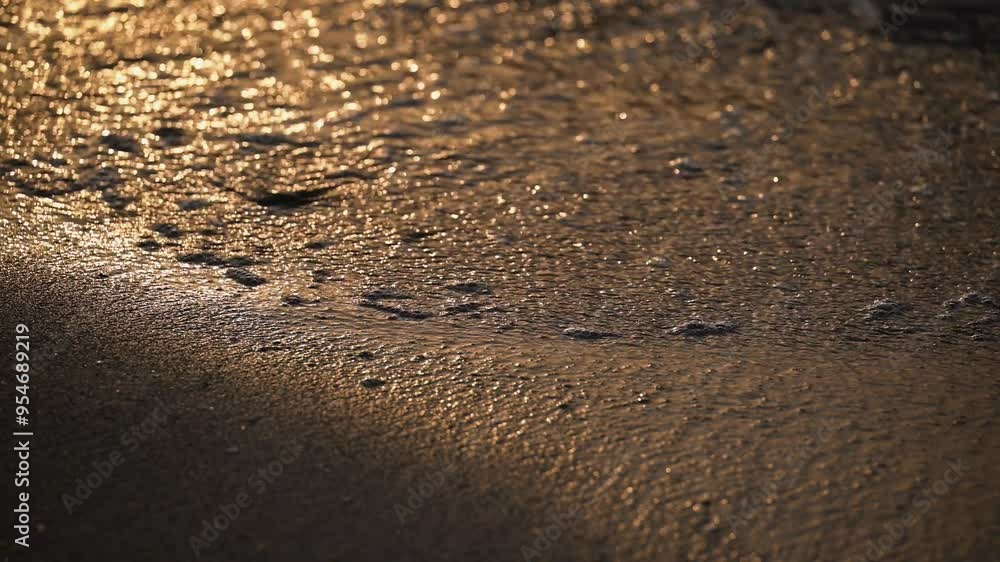 Waves crashing against the shore, forming foam on a beach during sunset Waves crashing against the shore, forming foam on a beach during sunset