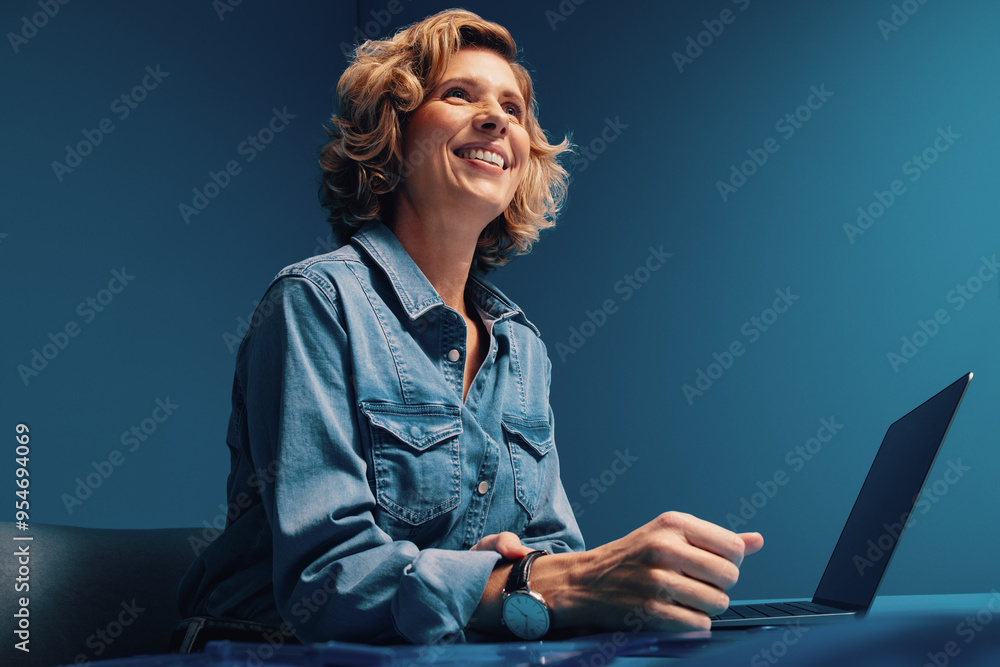 © Jacob Lund - Mature blonde woman with short hair working on laptop in monochromatic office