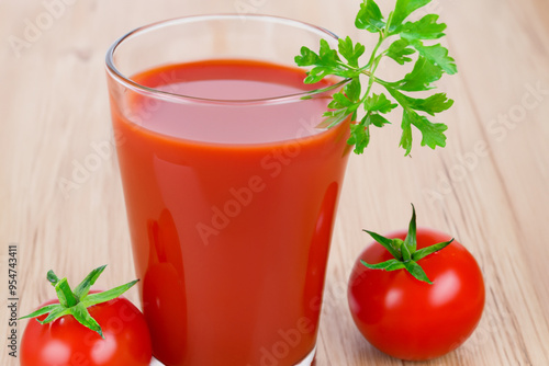 Table with tomatoes, parsley, and juice. vegan mix smoothie concept. a man drinking tomato juice on a wooden table with glasses. a table with a glass of juice and tomatoes next to parsley lifestyle.