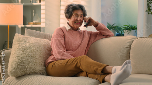 Relaxed happy laughing old woman on cozy sofa talking on smartphone laugh discuss funny news carefree smiling senior grandmother at comfy couch at home elderly lady female retired speak mobile phone