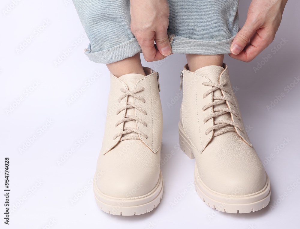 Female legs in jeans and white leather boots on white background. Fashion concept Female legs in jeans and white leather boots on white background. Fashion concept