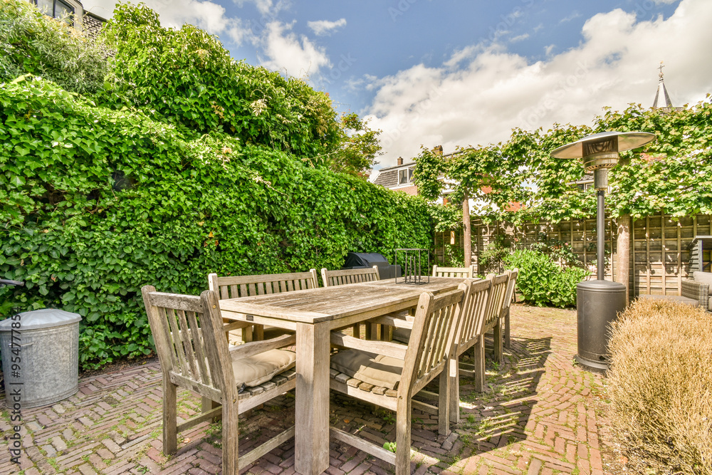 Cozy backyard patio with lush greenery and wooden furniture Cozy backyard patio with lush greenery and wooden furniture