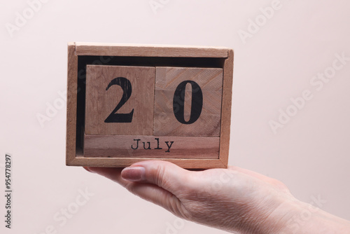 Wallpaper Mural Female Hand holding wooden block calendar with the date July 20 on beige background Torontodigital.ca