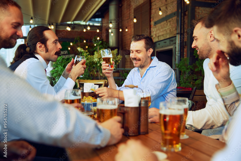 Business people, men enjoying relaxed meeting at the bar, with beers in hand, discussing business plans and celebrating growth. Concept of business, meeting, celebration, leisure time, Oktoberfest Business people, men enjoying relaxed meeting at the bar, with beers in hand, discussing business plans and celebrating growth. Concept of business, meeting, celebration, leisure time, Oktoberfest