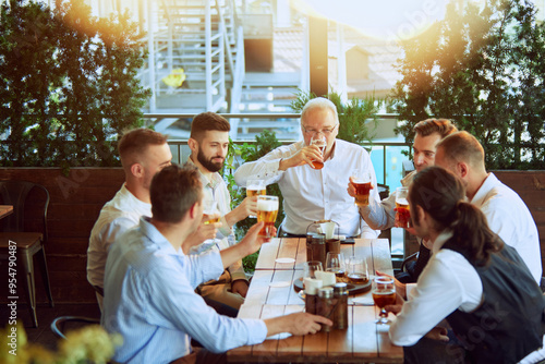 Photography Productive meeting, businessmen in formal wear gathering at outdoor bar, drinking beer, talking, laughing and relaxing after hard working week
