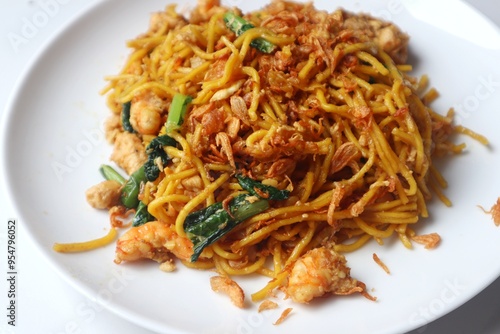 Delicious fried yellow noodles on a white plate close up view.