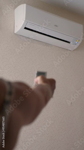 woman turns on air conditioner with remote