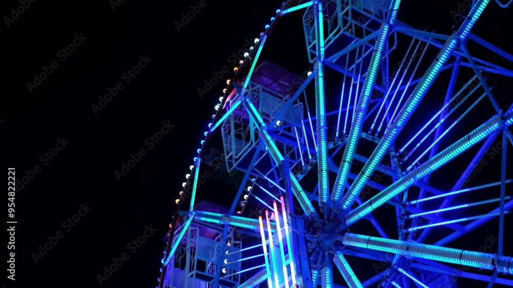 Ferris wheel at night. Ferris wheel and roller coaster in motion at amusement park at night. Ferris wheel at night. Ferris wheel and roller coaster in motion at amusement park at night.