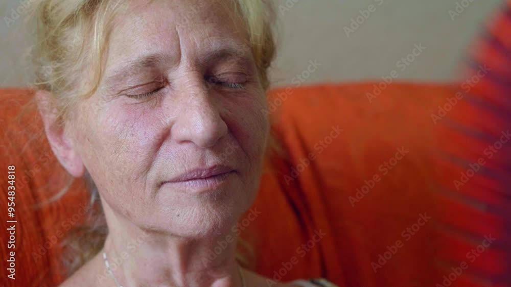 Mature woman finds relief with a red fan indoors during intense heat