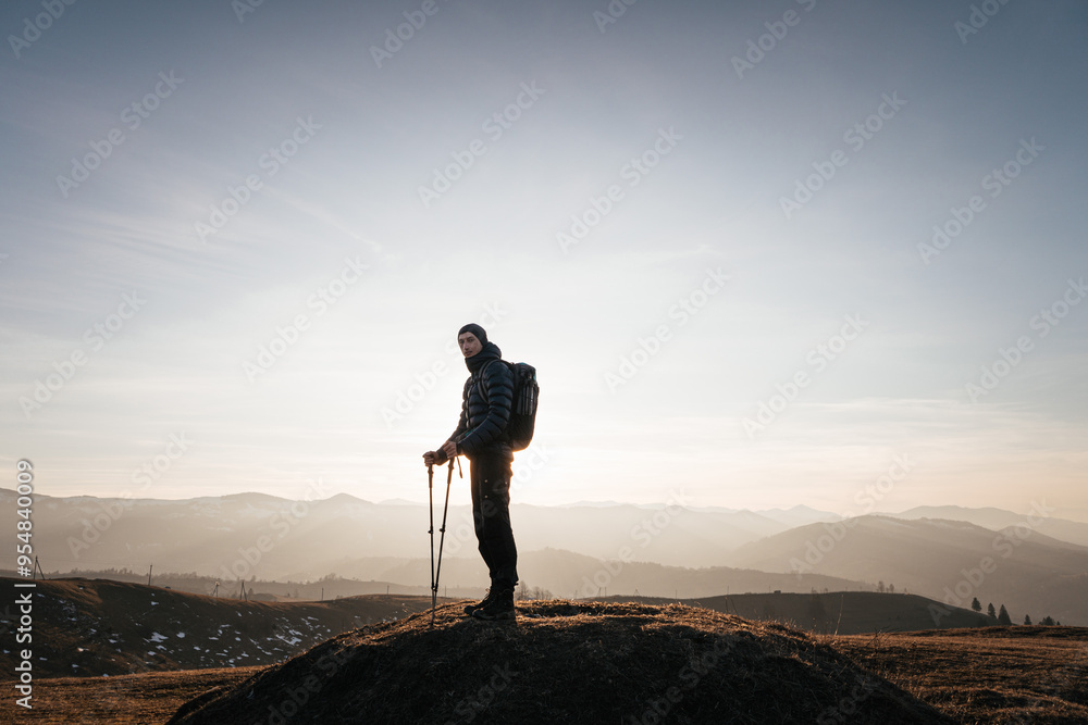 Obraz premium Solo hiker on mountain at sunrise with trekking poles