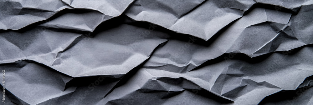 Heavily crumpled grey paper texture with deep lines and shadows rough and weathered appearance Heavily crumpled grey paper texture with deep lines and shadows rough and weathered appearance