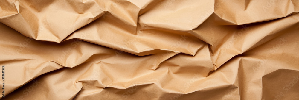 Lightly wrinkled scrunched up kraft paper background with textured creases and natural brown tones Lightly wrinkled scrunched up kraft paper background with textured creases and natural brown tones