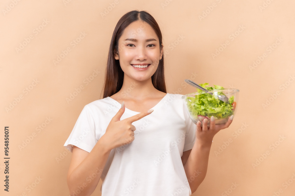 A happy asian people in white shirts, holding glasses of milk and a bowl of salad, against a beige background. A happy asian people in white shirts, holding glasses of milk and a bowl of salad, against a beige background.