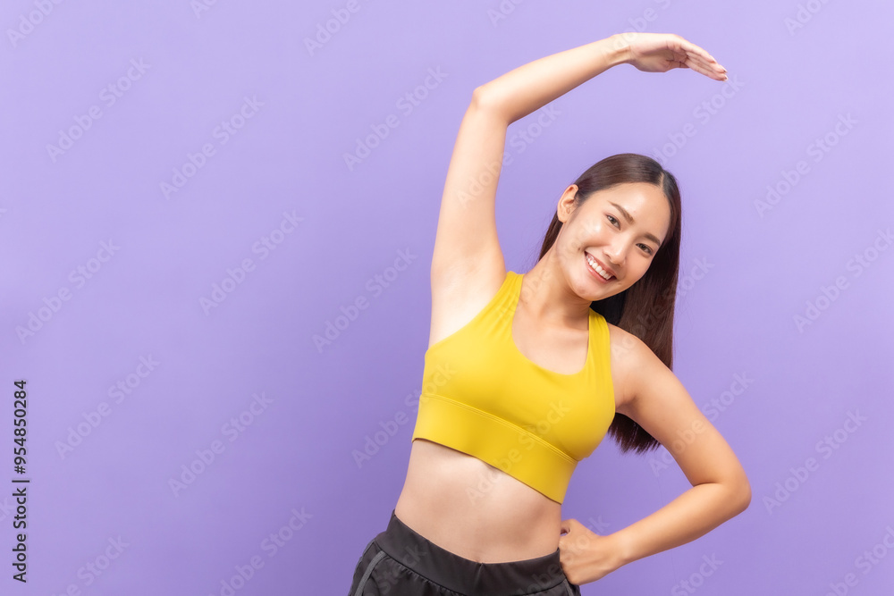 Smiling asian woman in yellow sportswear performing a fitness stretch, set against a bold purple background. Smiling asian woman in yellow sportswear performing a fitness stretch, set against a bold purple background.