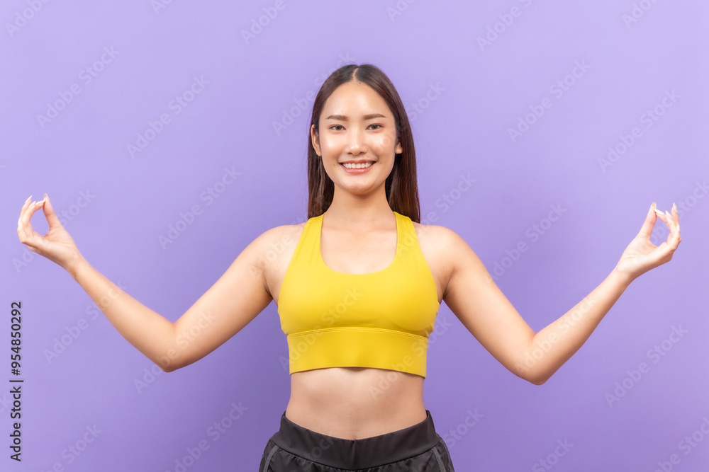 Smiling  asian woman in yellow sportswear performing a fitness stretch, set against a bold purple background.