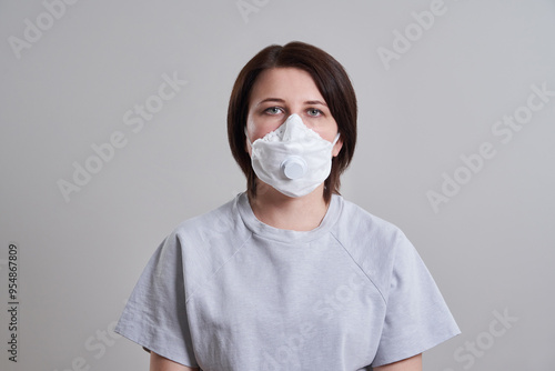 Young woman wearing surgical mask for protection from coronavirus over grey background with copy space