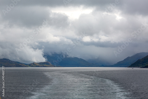 View of the entrances to Loch Hourn and Loch Nevis from the back of a ferry in the Atlantic on a cloudy morning, Image shows the Scottish mainland hills covered in cloud and calm waters with a wake photo