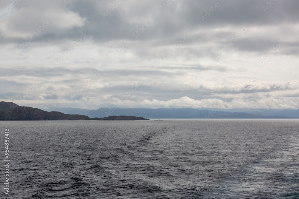 View of Scottish mainland from a ship, Image shows beautiful landscape coastal views of the mainland from a ship following the coastline image shows calm seas with heavy cloud and hilly terrain View of Scottish mainland from a ship, Image shows beautiful landscape coastal views of the mainland from a ship following the coastline image shows calm seas with heavy cloud and hilly terrain