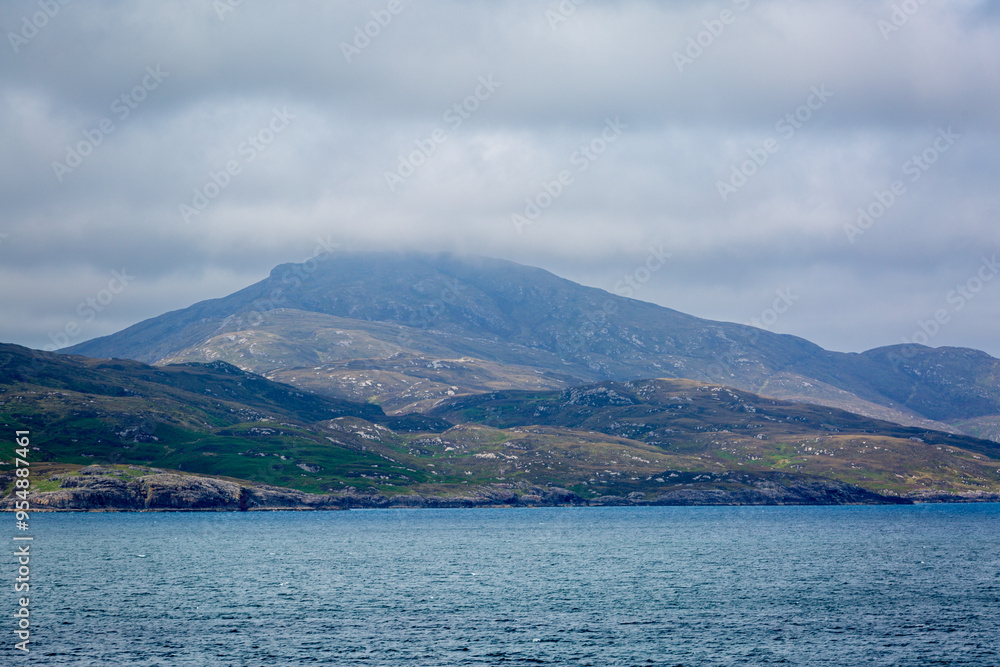 View of Scottish mainland from a ship, Image shows beautiful landscape coastal views of the mainland from a ship following the coastline image shows calm seas with heavy cloud and hilly terrain View of Scottish mainland from a ship, Image shows beautiful landscape coastal views of the mainland from a ship following the coastline image shows calm seas with heavy cloud and hilly terrain