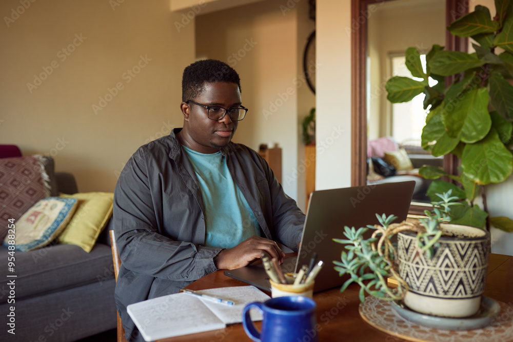 Fototapeta premium Young African man working remotely from home using a laptop