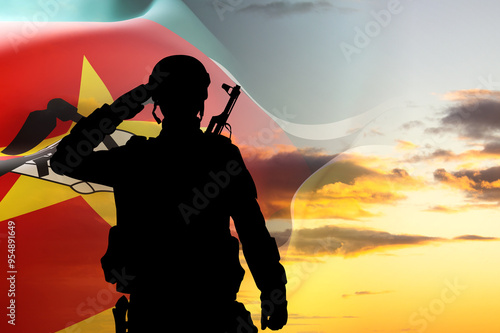 Silhouette of a soldier with Mozambique flag against the sunset. National Holidays concept