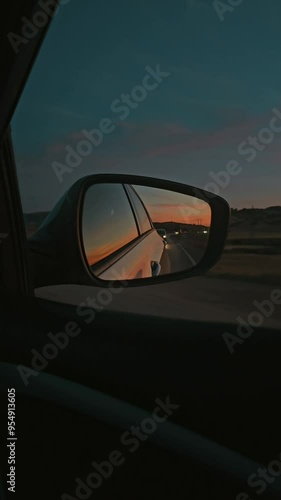 The sun is reflected in the mirror, evening road. View in the rear view side mirror of a auto, driving a  car along the track in north of Morocco