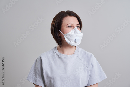 Young woman wearing face mask for protection from corona virus over grey background with copy space