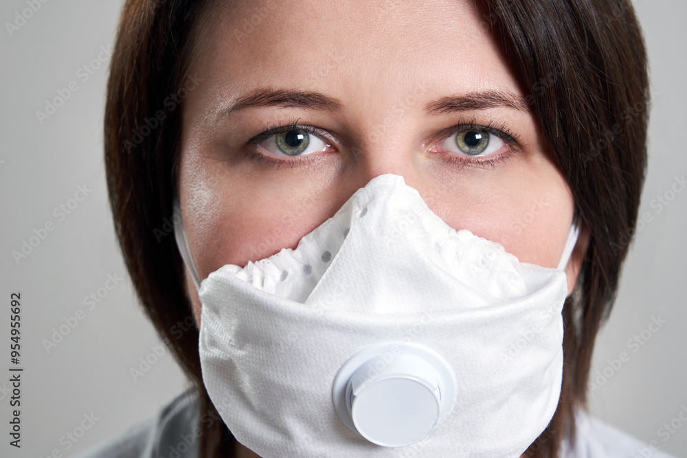 Young woman wearing face mask for protection from coronavirus over grey background with copy space Young woman wearing face mask for protection from coronavirus over grey background with copy space