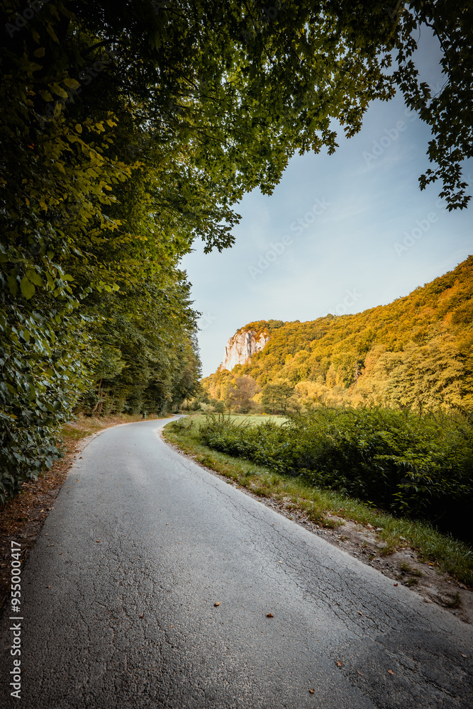 Beautiful autumn landscape. The setting sun illuminating the limestone rocks. An asphalt road winding through the valley. Bedkowska Valley. Jura. Poland