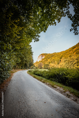 Obraz na płótnie Beautiful autumn landscape. The setting sun illuminating the limestone rocks. An asphalt road winding through the valley. Bedkowska Valley. Jura. Poland w salonie