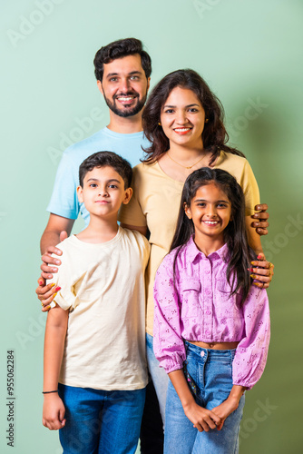 Sticker Happy Indian Asian family posing together against a green wall; parents with son
