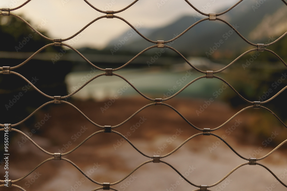 The blured view through metal grid to the mountain blue water lake in the north of italy The blured view through metal grid to the mountain blue water lake in the north of italy