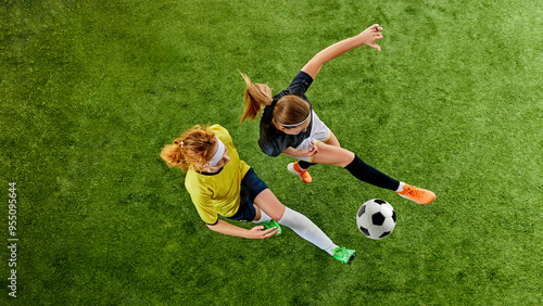Two athletic women  locked in fierce duel over ball  showcasing agility and skill  each fighting for dominance on soccer field. Aerial view. Concept of sport  competition  tournament  games  event.