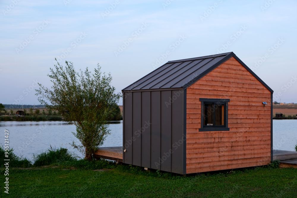 Small barn style house on a lakefront property under blue skies Small barn style house on a lakefront property under blue skies