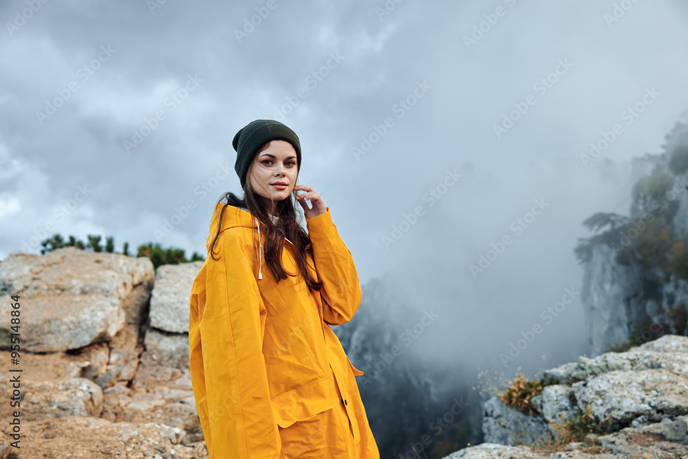 A woman in a yellow raincoat conquering the misty mountain top in a breathtaking travel adventure A woman in a yellow raincoat conquering the misty mountain top in a breathtaking travel adventure